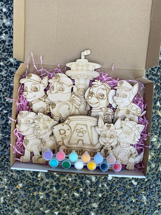 Wooden toys resembling characters from a popular children's show, displayed in a box with purple tissue paper.