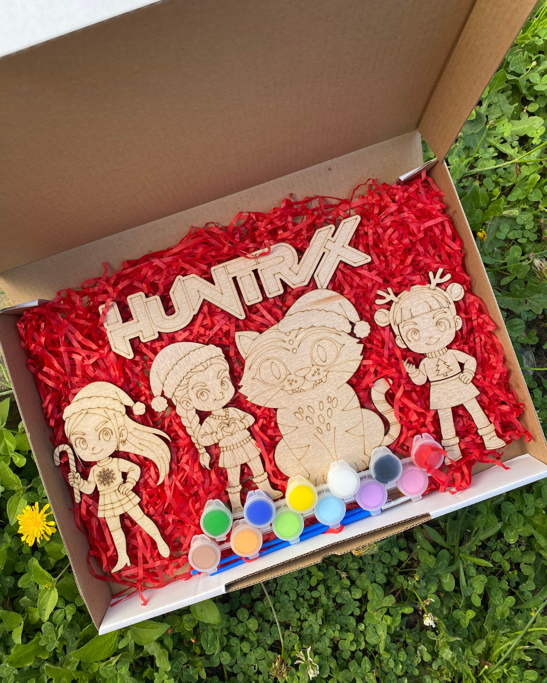 Wooden toys with paint supplies in a box on grass