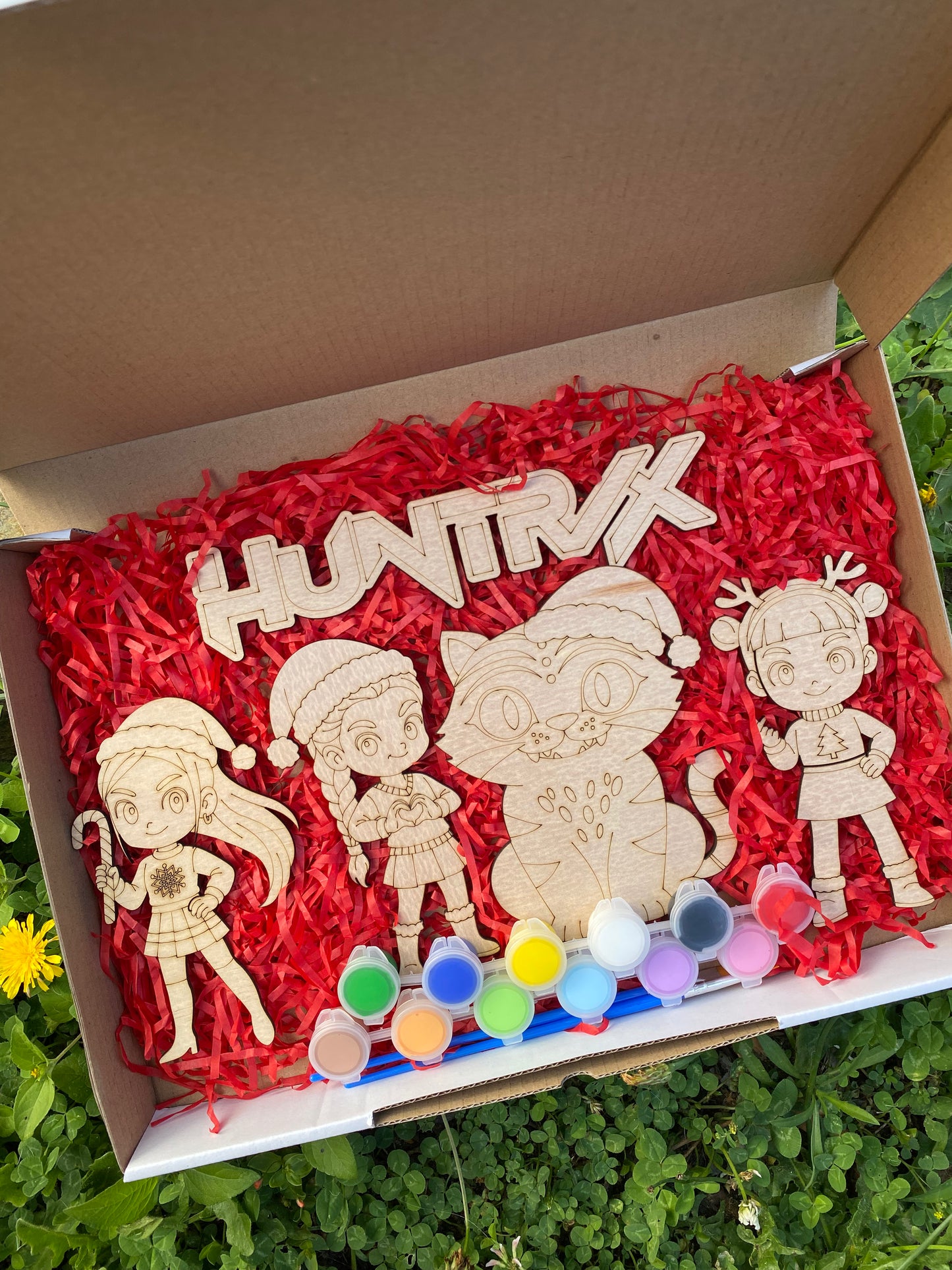 Wooden toys with 'HUNTRX' branding on a red shredded paper background