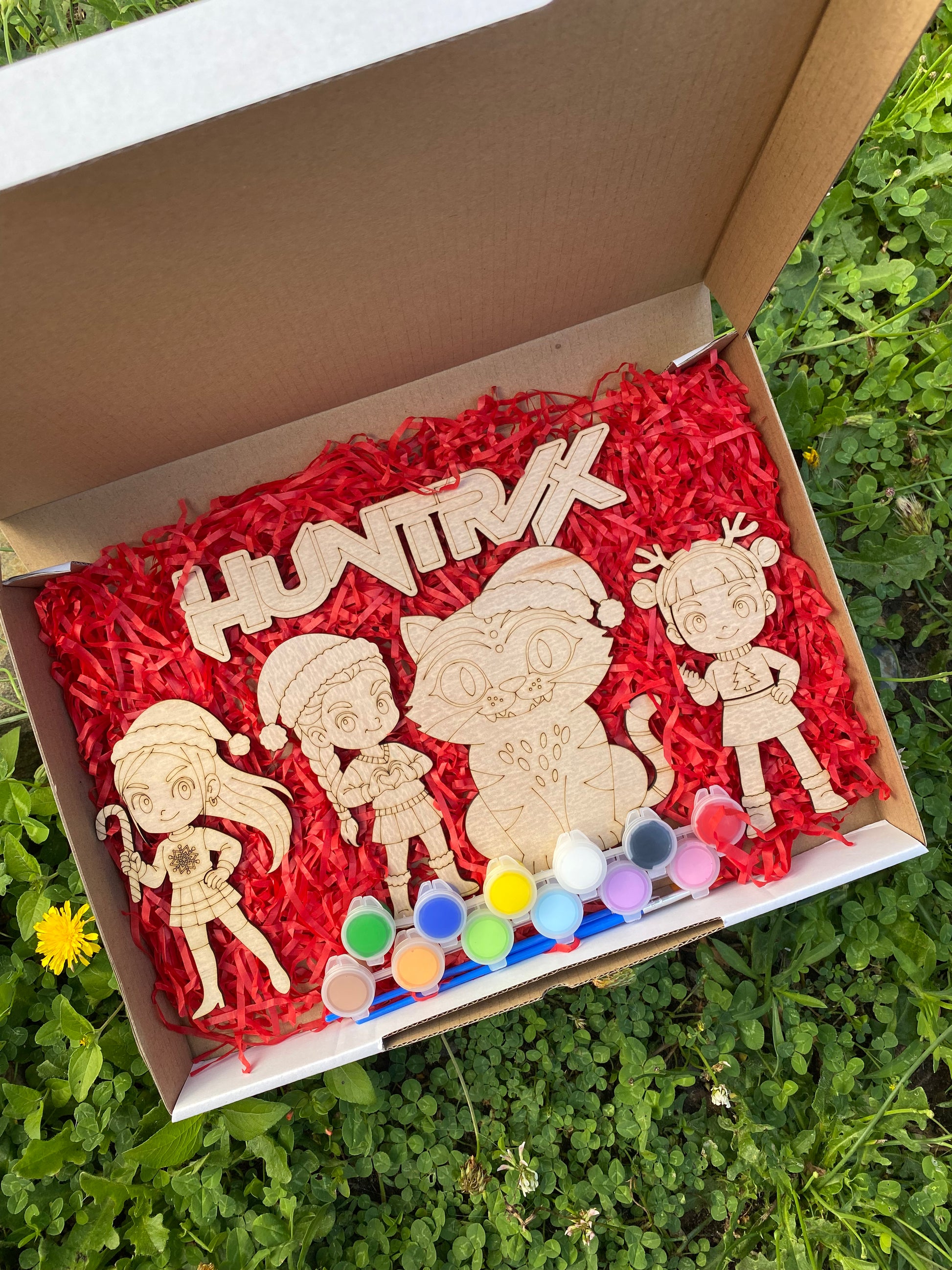 Wooden toys with paint supplies in a box on grass